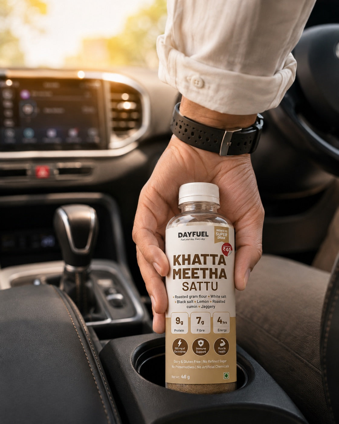 A hand setting a bottle of Dayfuel Khatta Meetha Sattu into a car cup holder