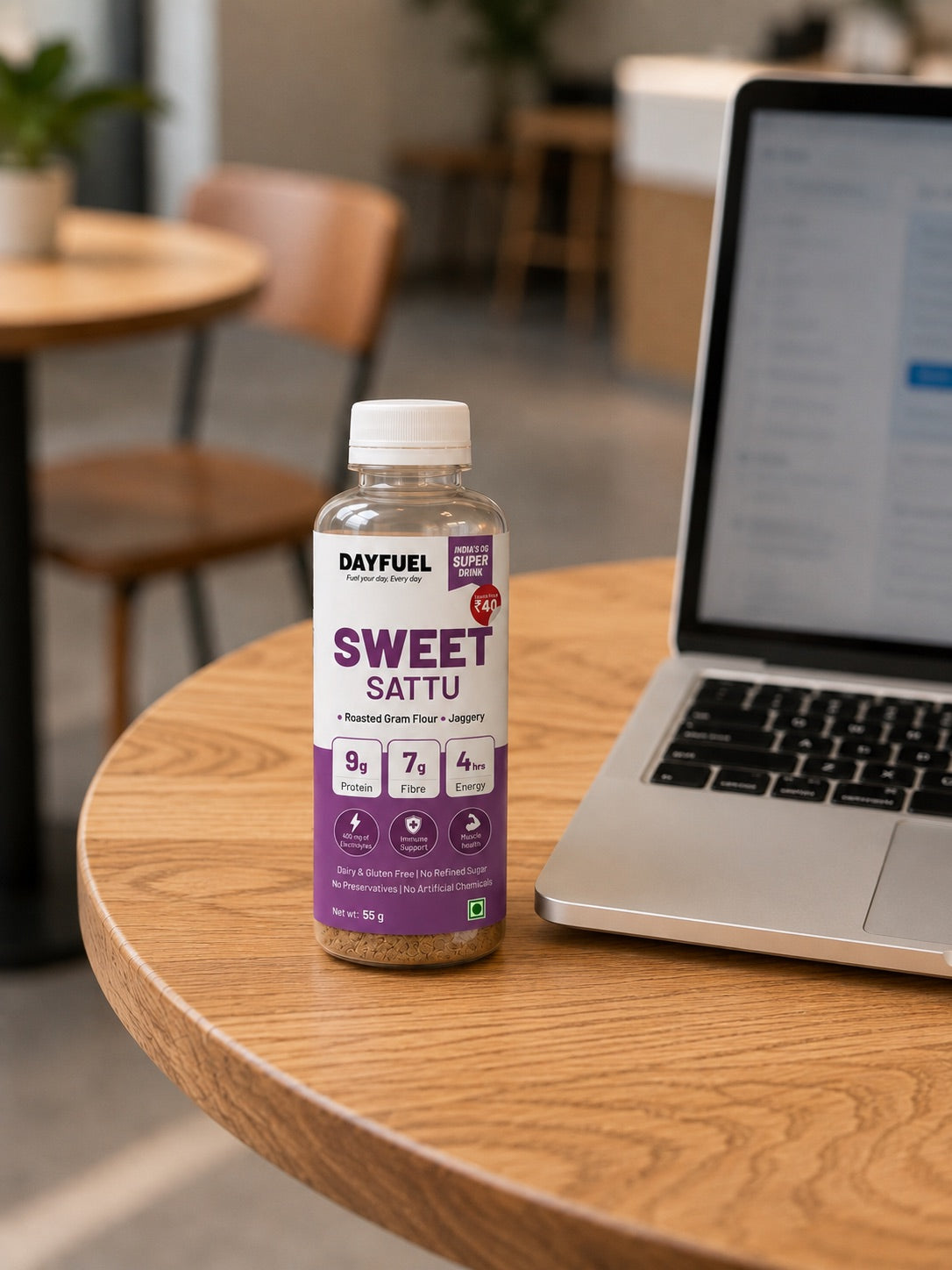 A bottle of Dayfuel Sweet Sattu on a cafe table beside an open laptop